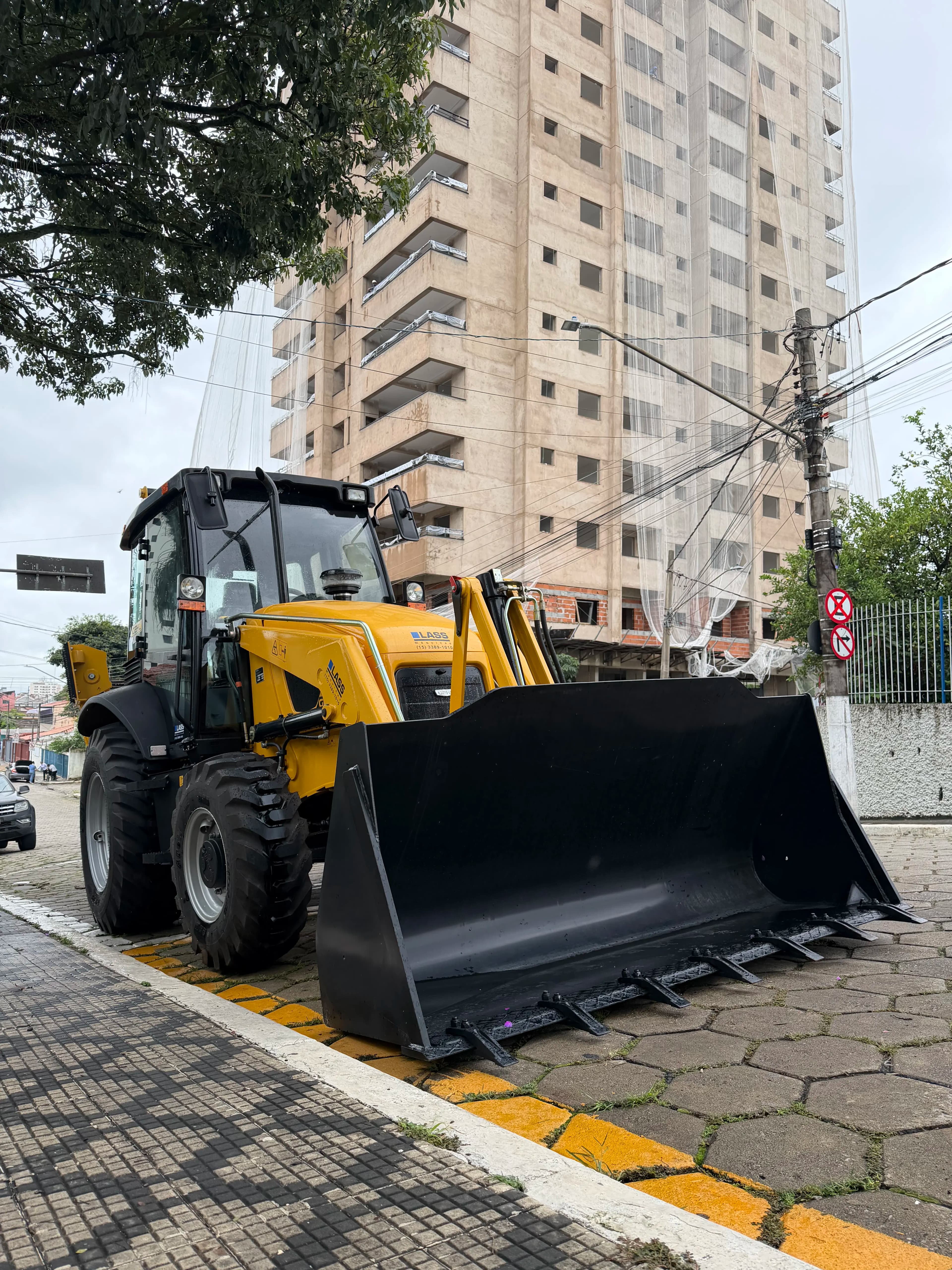 Retroescavadeira amarela em área urbana